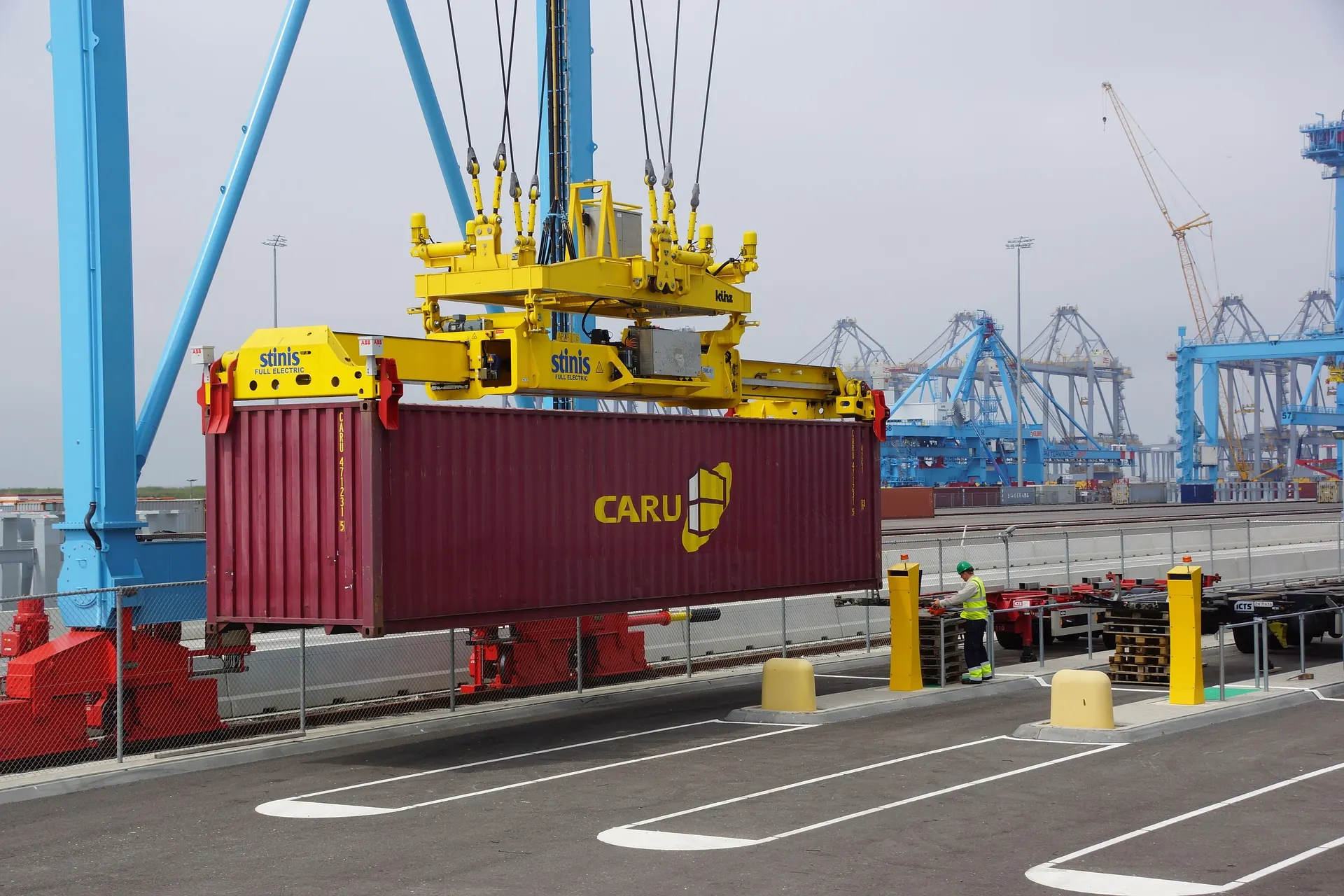 A crane spreader lifting a container onto the quay